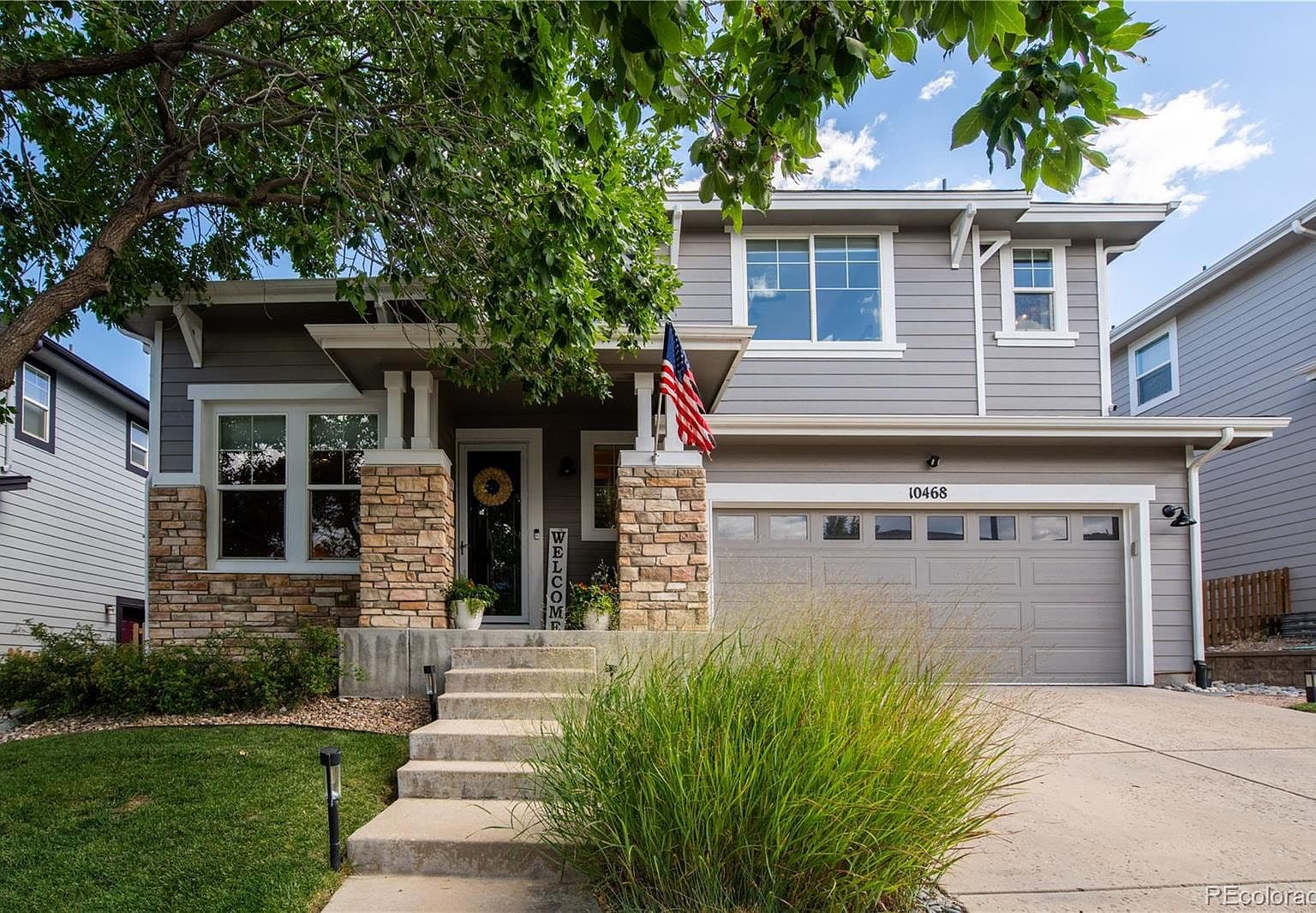 Inviting front exterior with stone accents and mature shade tree.