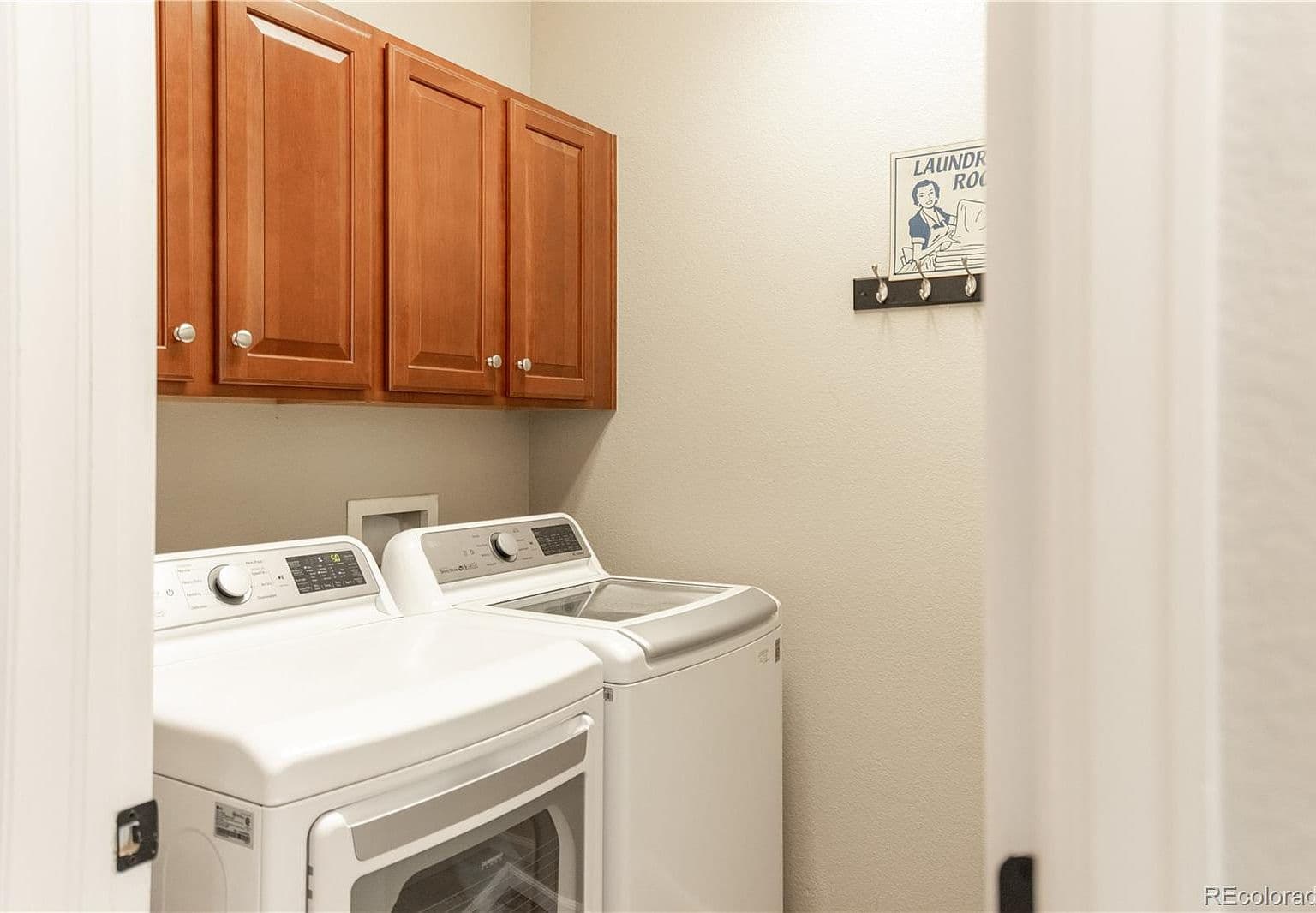 Main-level laundry room with cabinets and side-by-side machines.