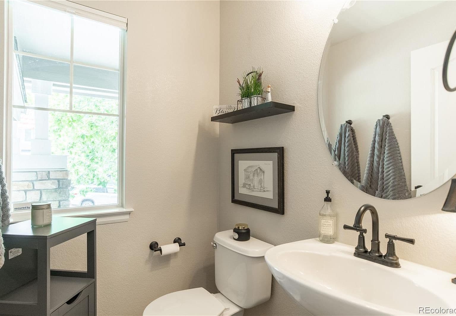 Stylish powder bath with round mirror and natural light.