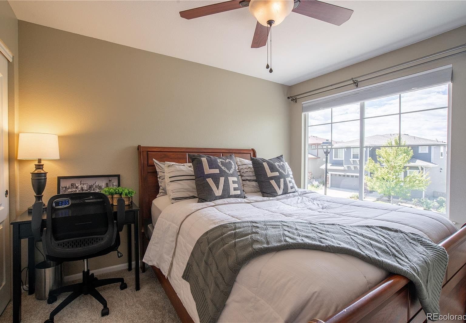 Peaceful bedroom with large window and ceiling fan.