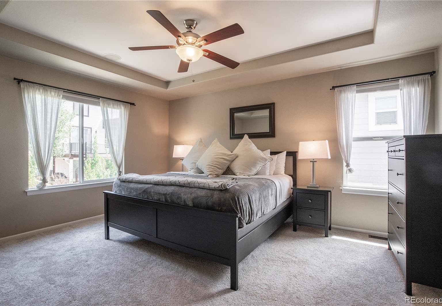 Serene primary suite with tray ceiling and plush carpet.
