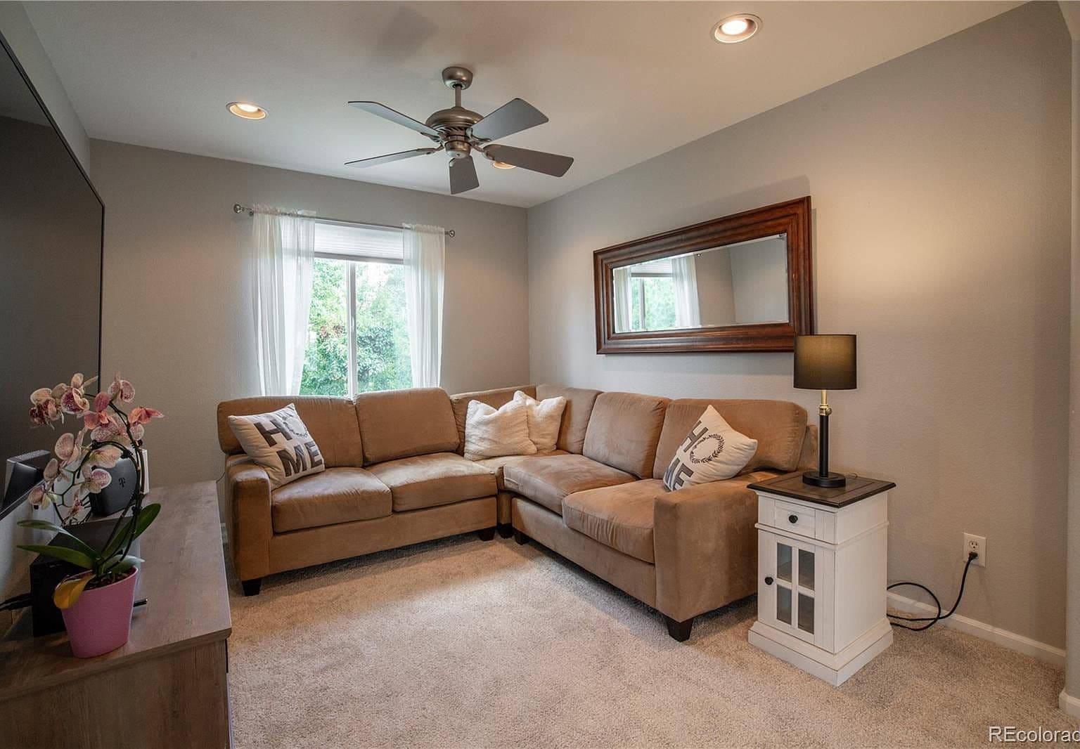 Inviting loft retreat with ceiling fan and soft carpeting.