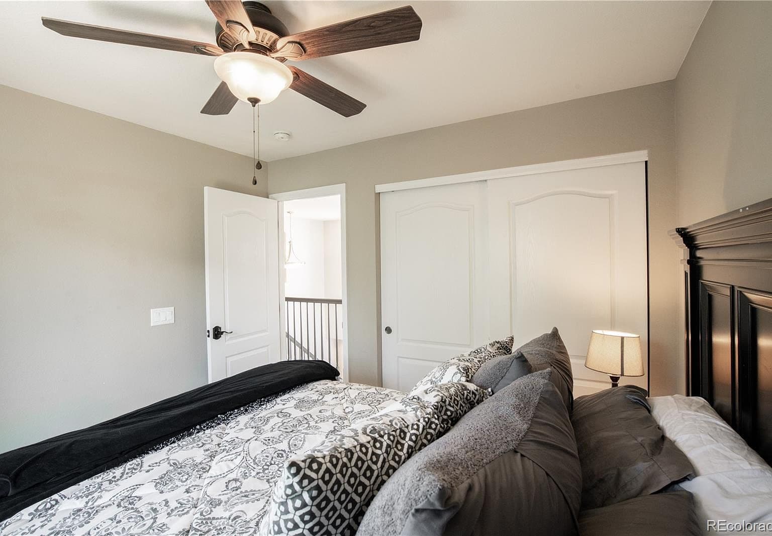 Secondary bedroom with sliding closet doors and ceiling fan.