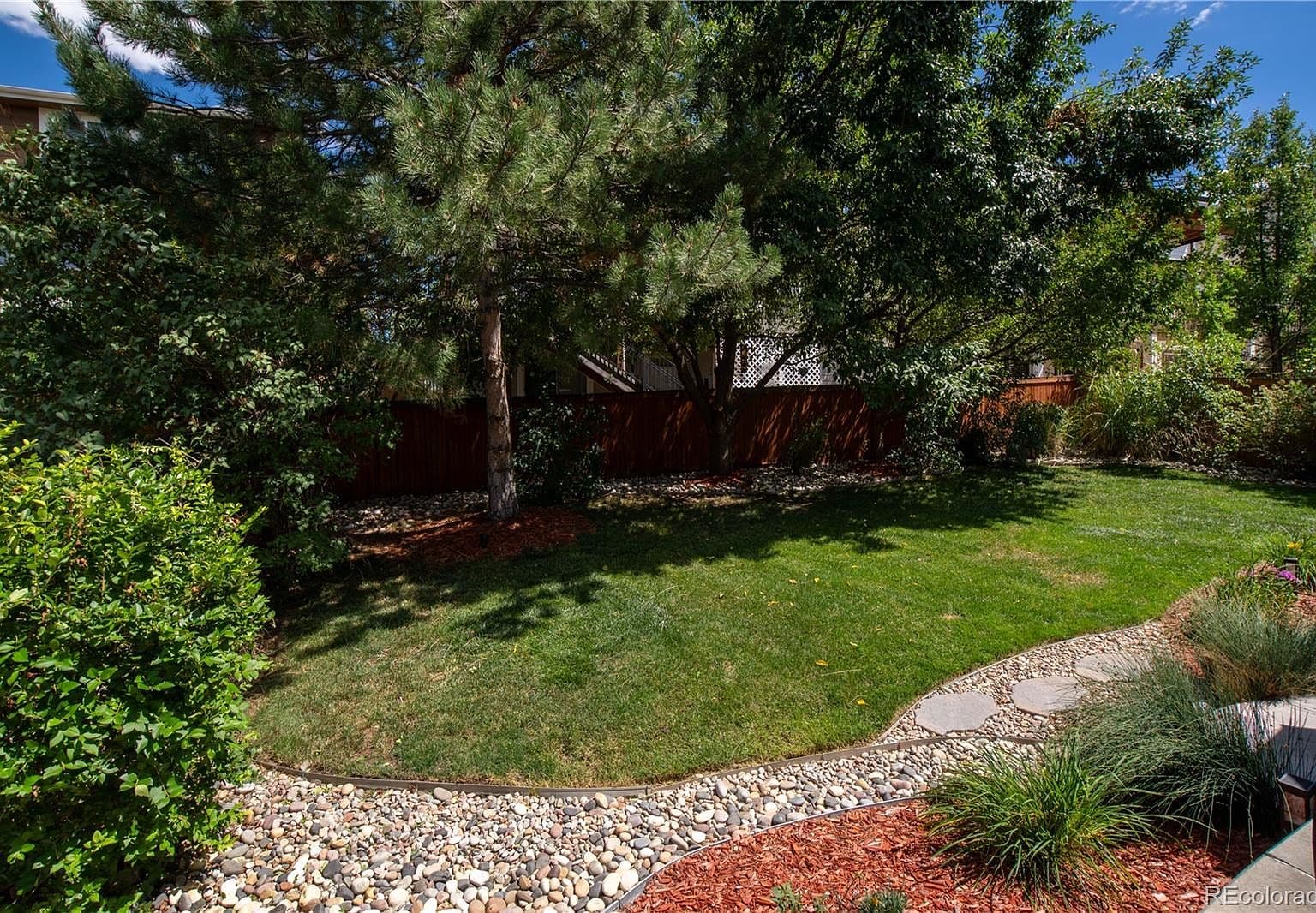 Lush, private backyard lawn framed by mature trees.