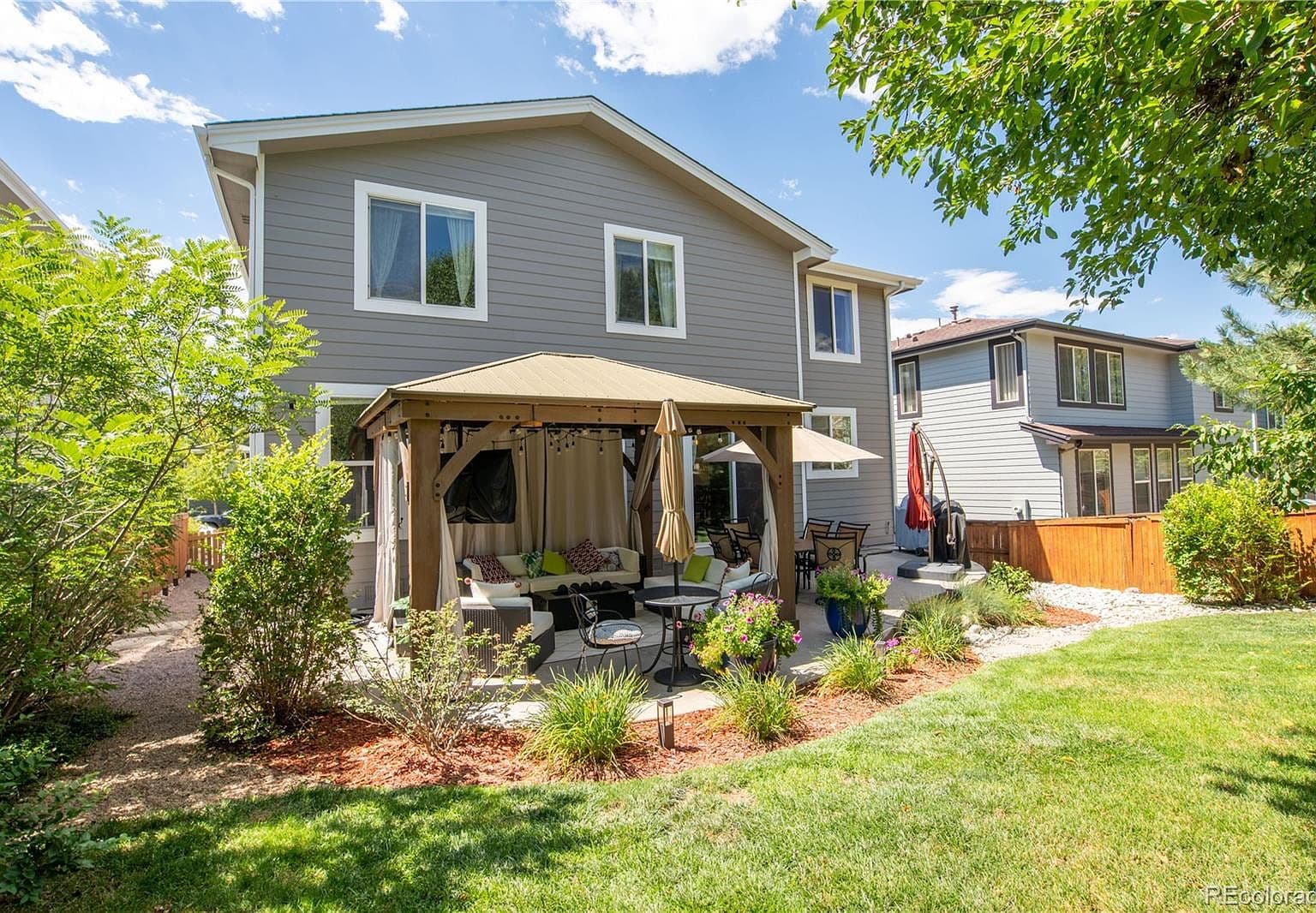 Backyard retreat with gazebo seating and sunny lawn.