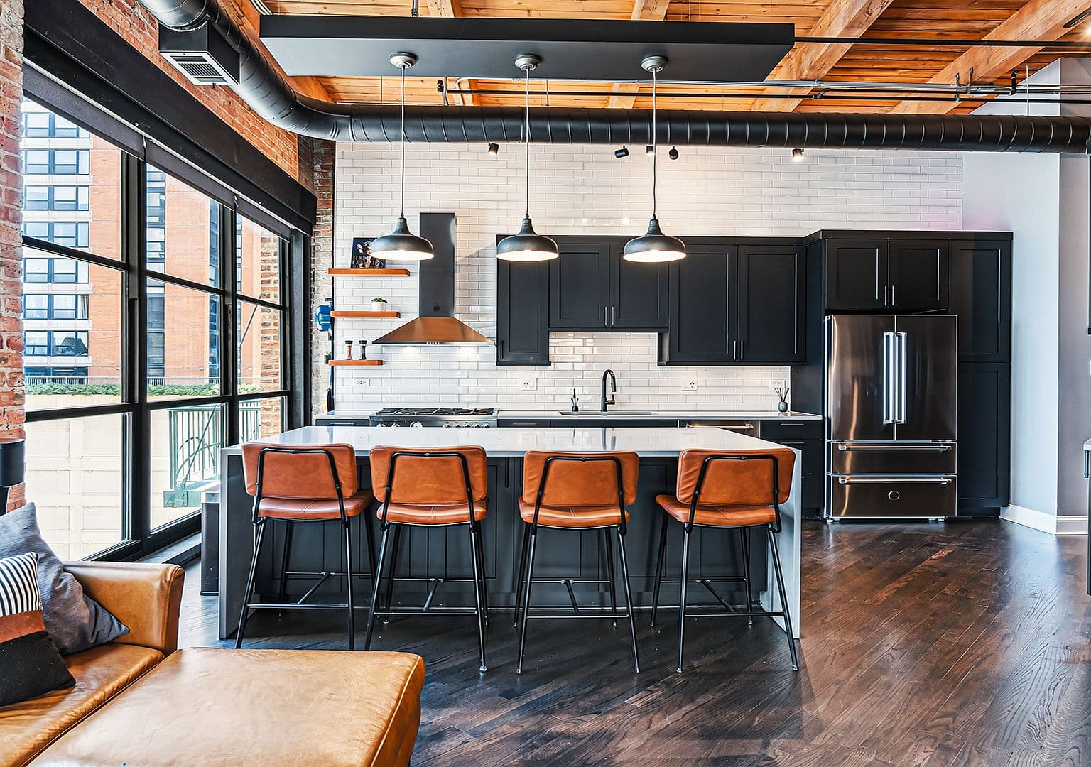 Oversized island with leather barstools and industrial pendant lighting