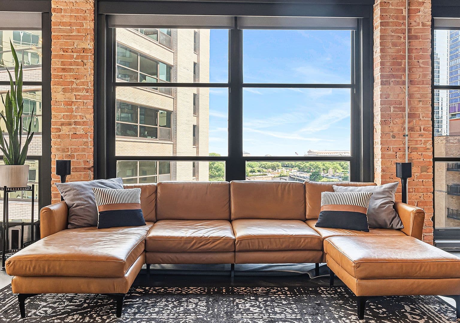 Leather sectional beneath towering windows with skyline views