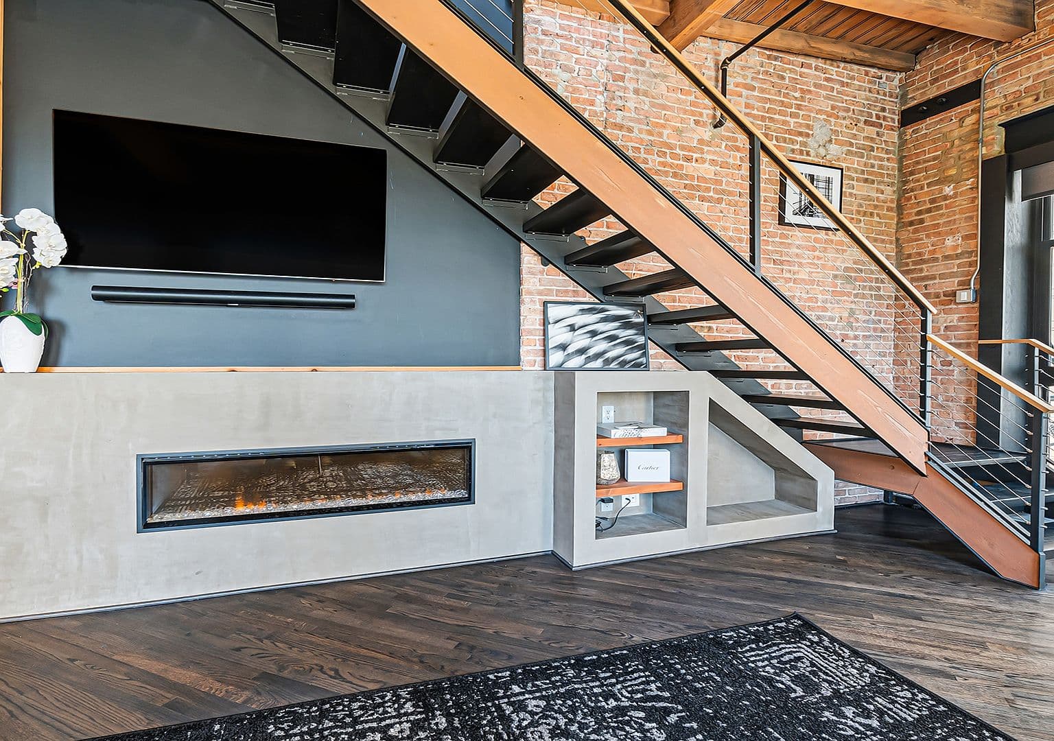 Floating steel staircase over concrete fireplace and media wall