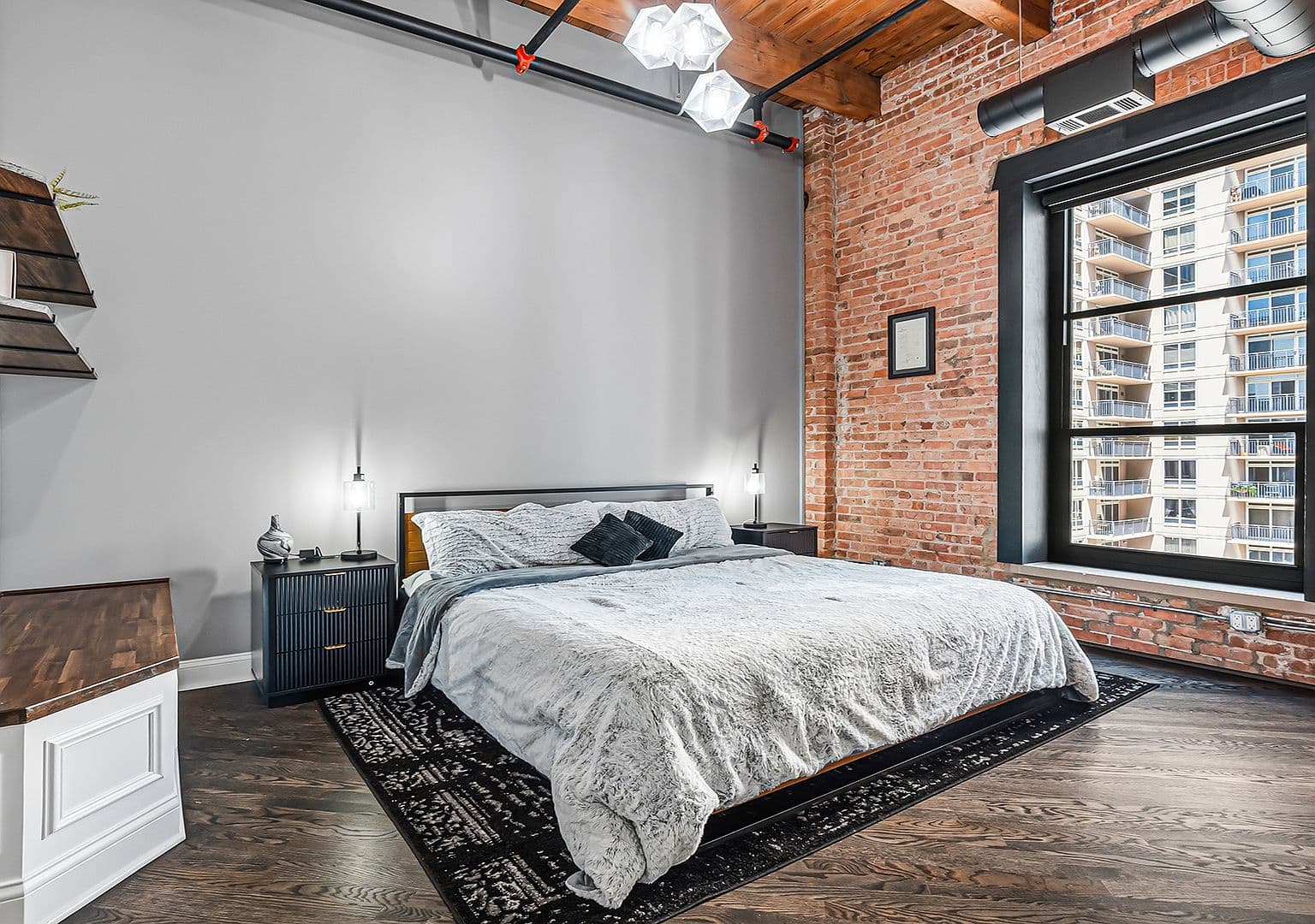Sunlit primary suite with exposed brick and soaring ceilings