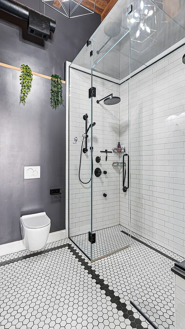 Glass-enclosed shower and floating toilet in the primary bath