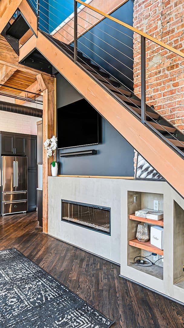 Timber-beam staircase over linear fireplace and built-in shelving
