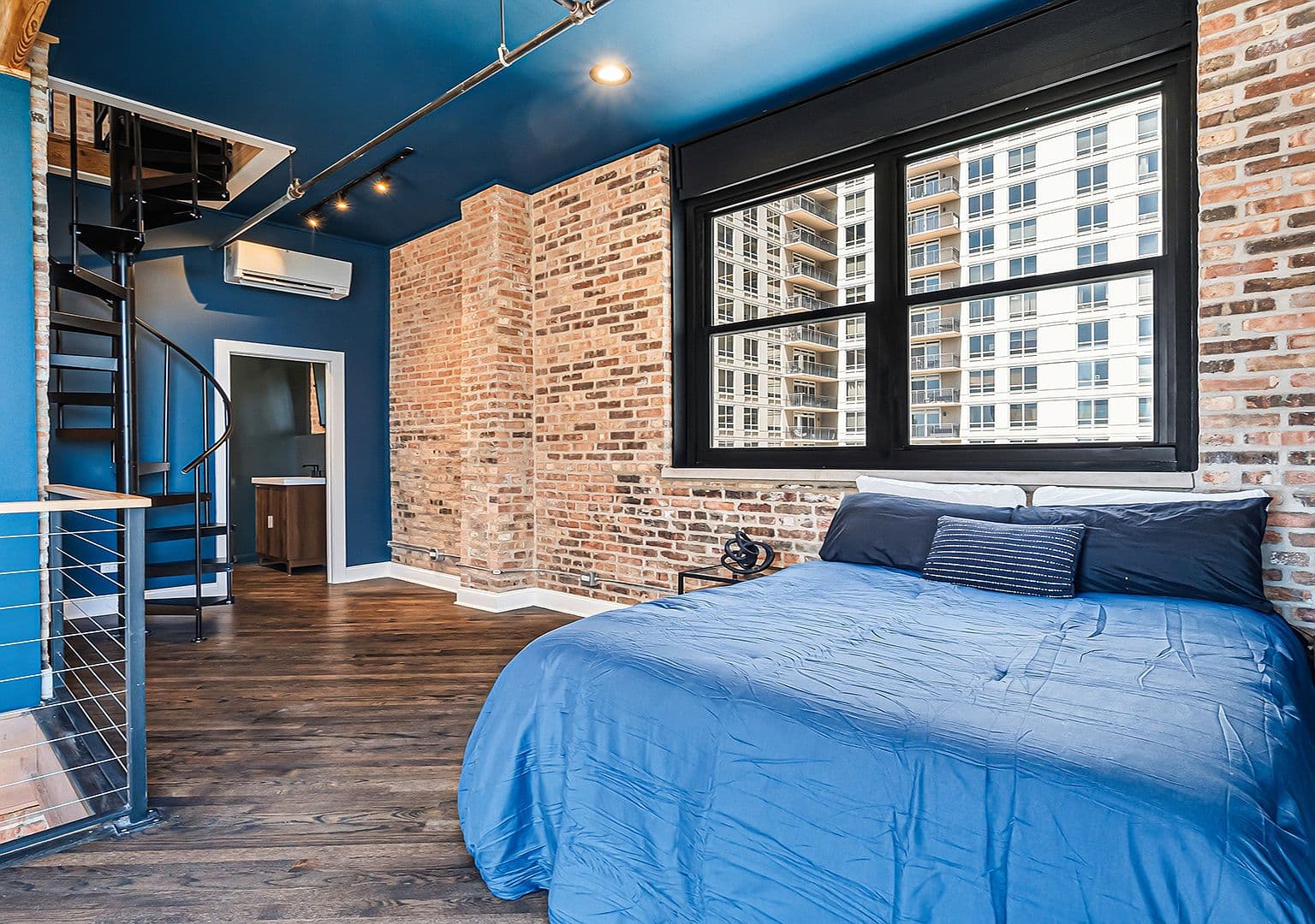 Second-level suite with exposed brick and spiral stair