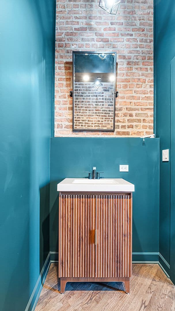 Powder room with fluted walnut vanity and exposed brick