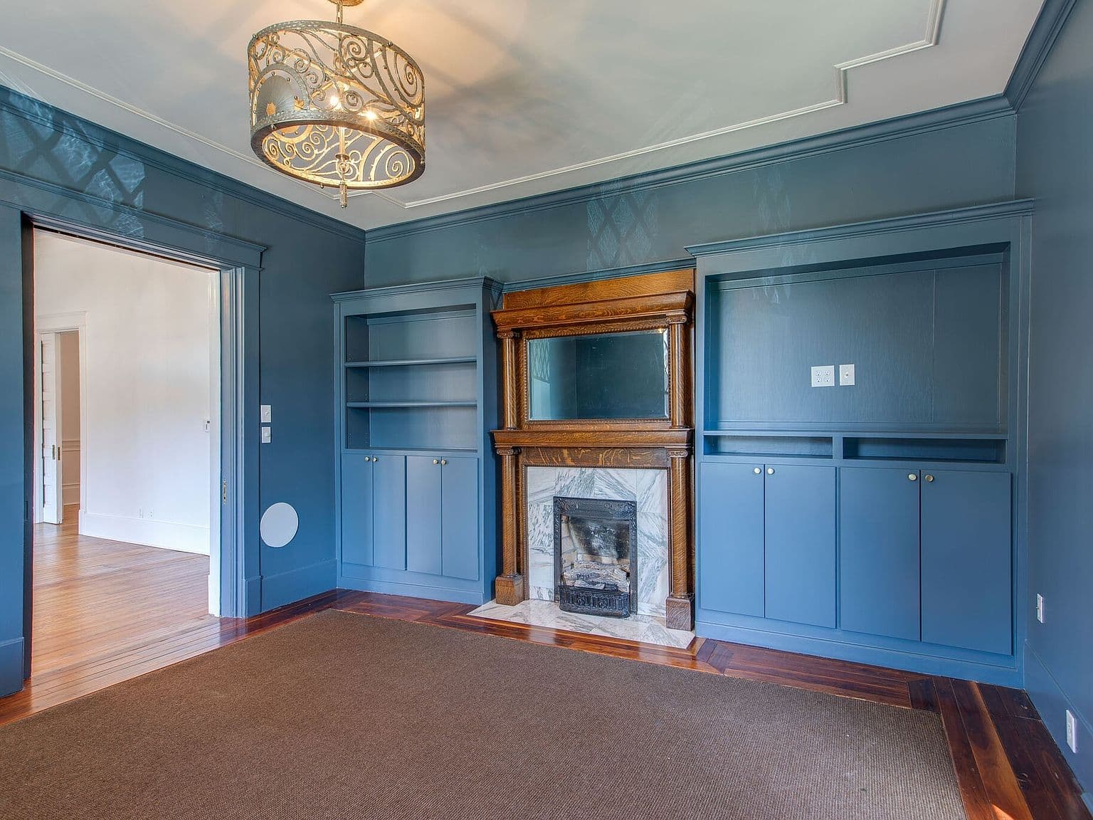 Moody blue study with hearth, built-ins, and chandelier.