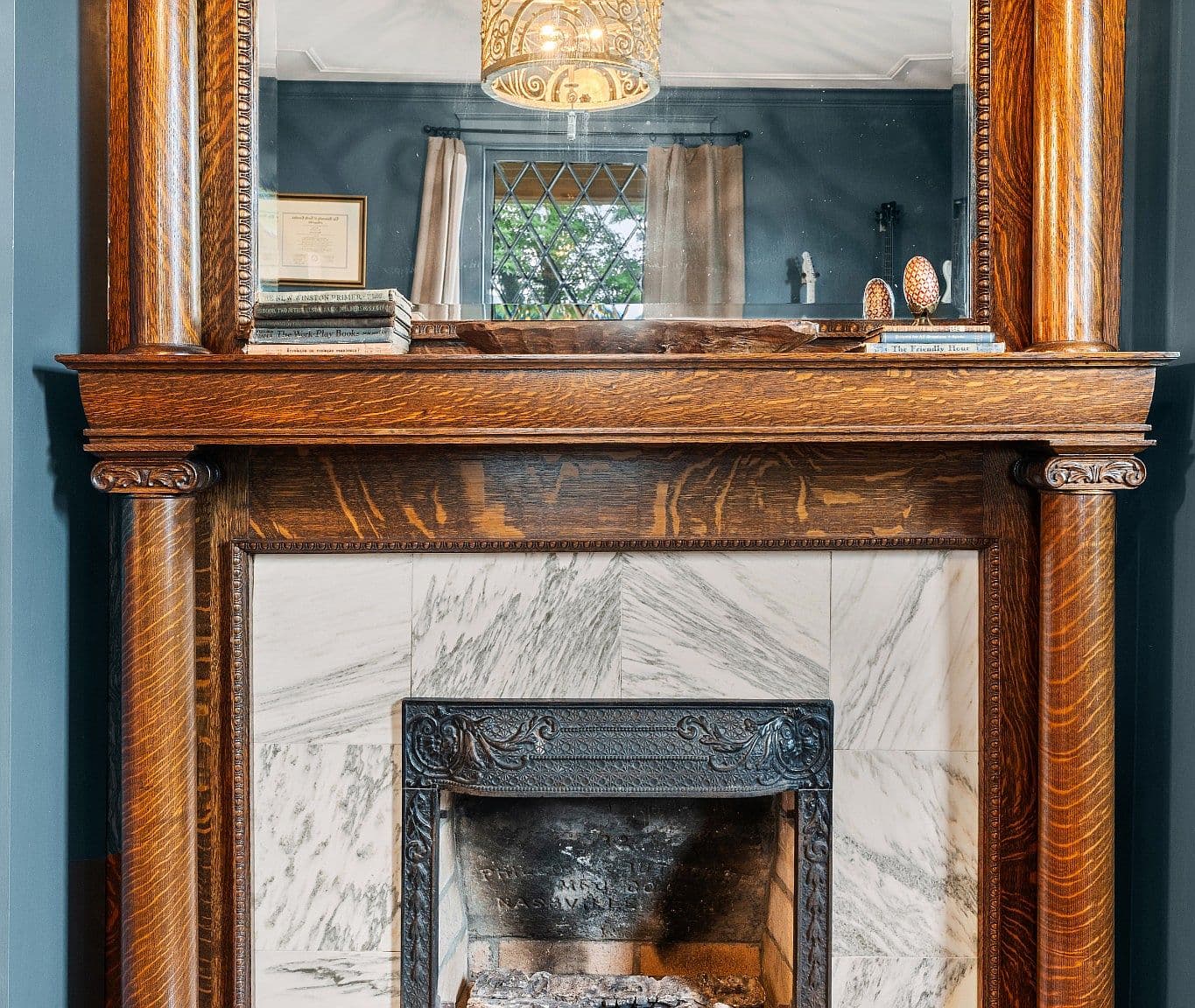 Close-up of original marble fireplace and carved wood mantel.