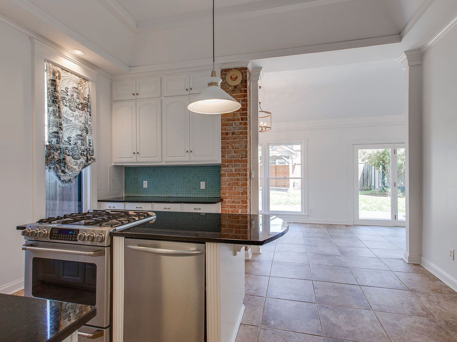 Chef’s kitchen with island, gas range, and backyard views.