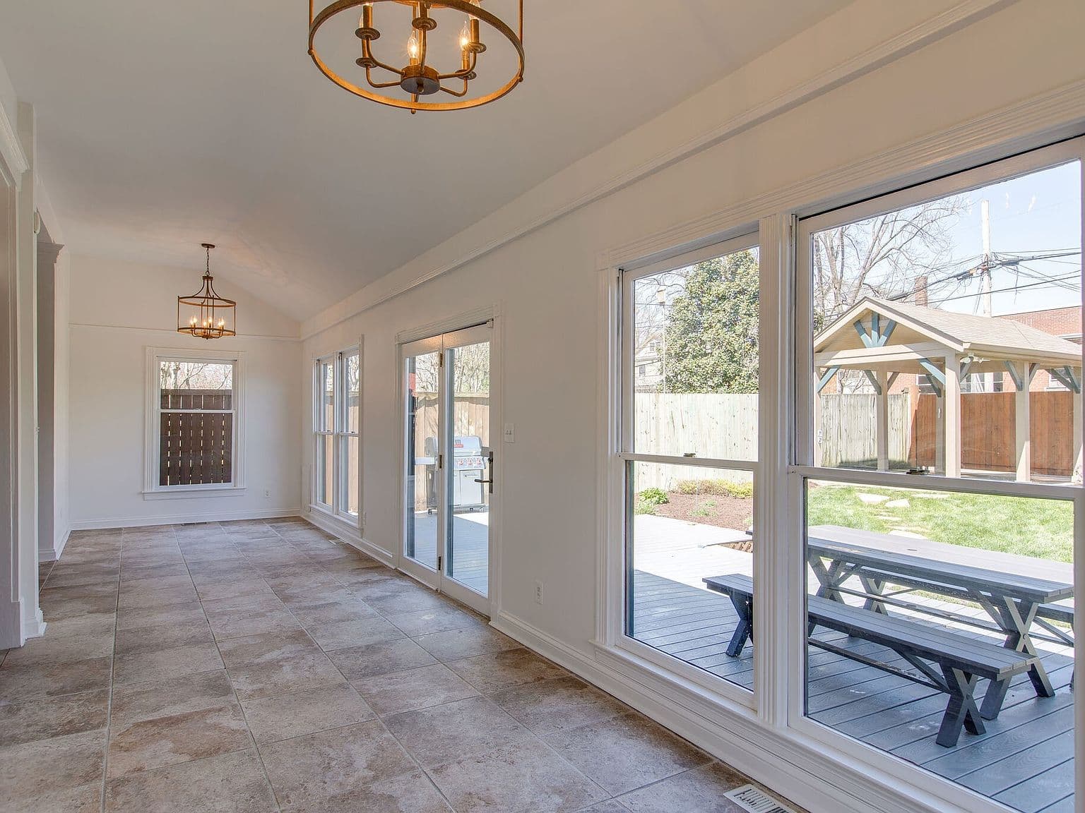 Long sunroom-style space with deck access and garden views.
