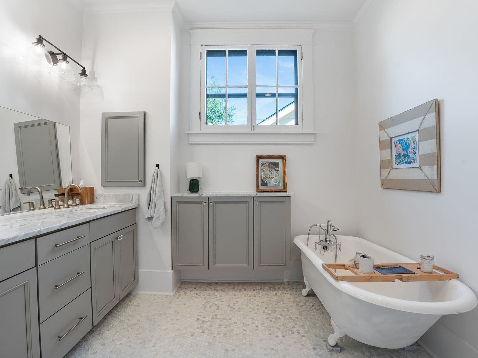 Light-filled bathroom featuring vintage-style tub and ample storage.