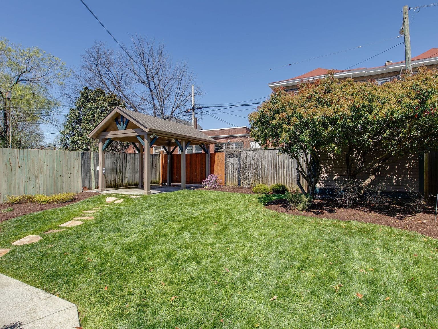 Private fenced backyard with lush lawn and alley access.