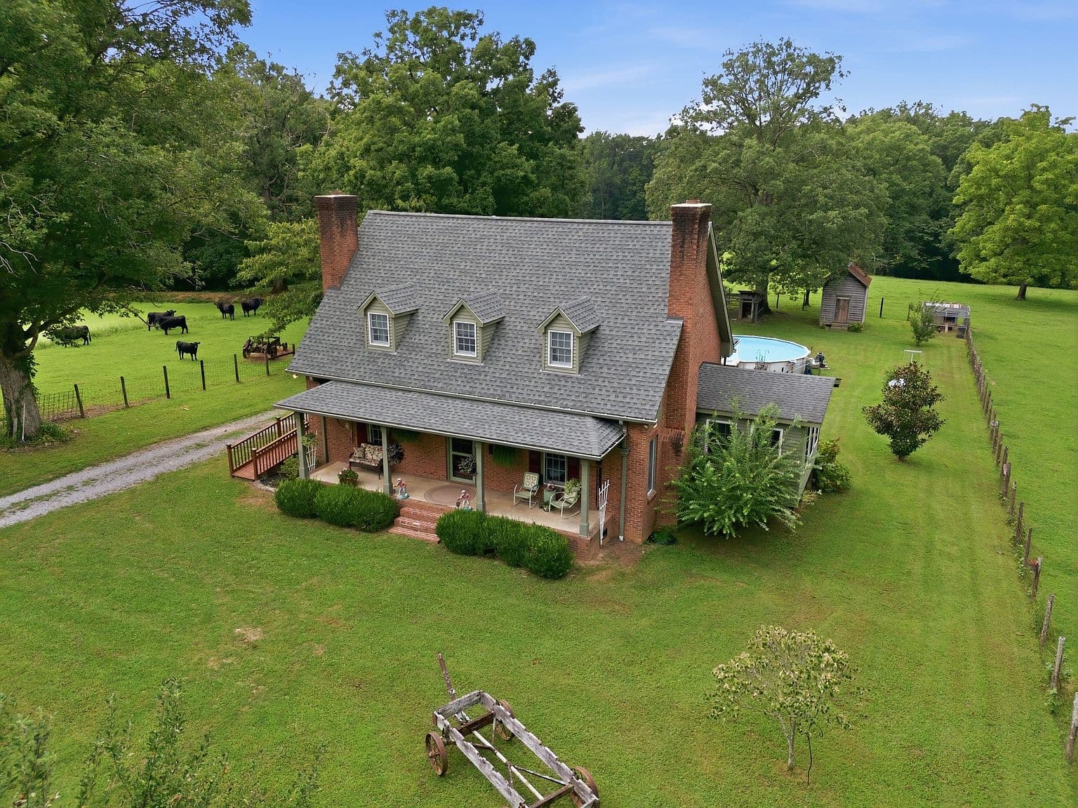 Aerial view of farmhouse, pool, and rolling pastureland.