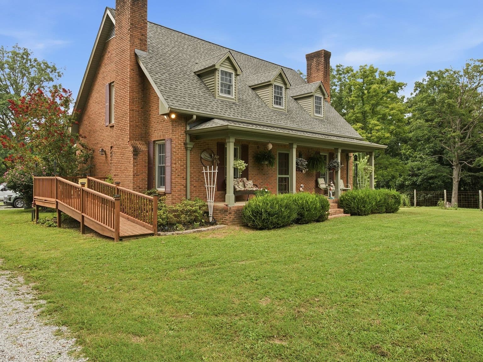 Charming brick exterior with deep porch and twin chimneys.