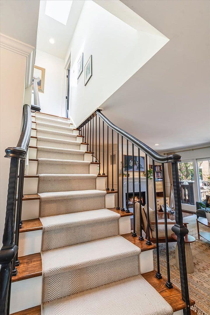 Elegant staircase overlooks living room and cozy fireplace.