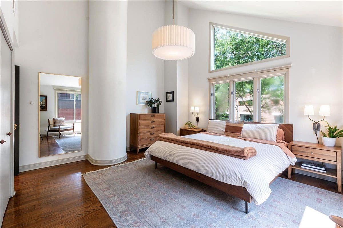 Vaulted primary suite with oversized windows and treetop views.