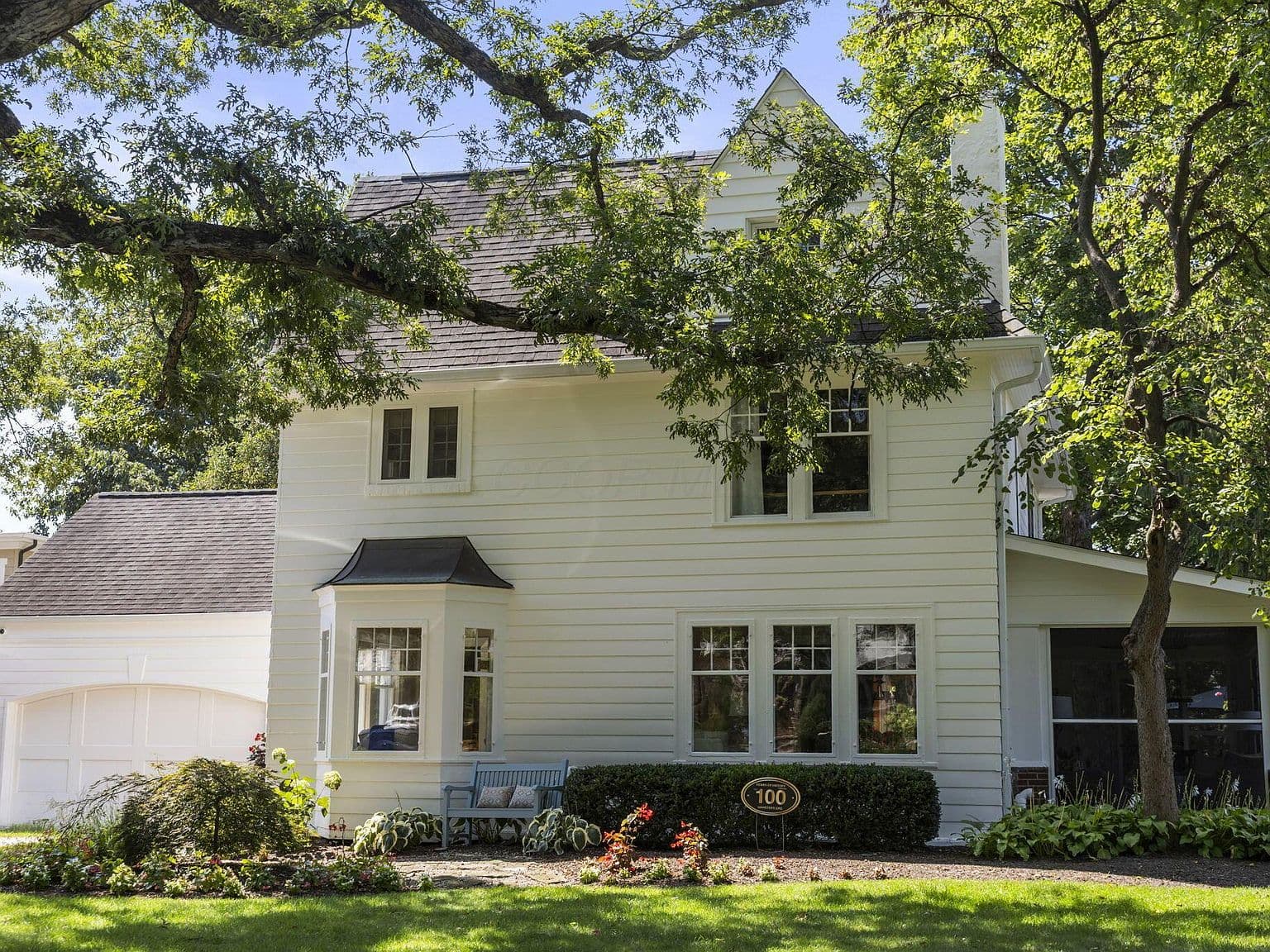 Storybook exterior nestled beneath mature shade trees.