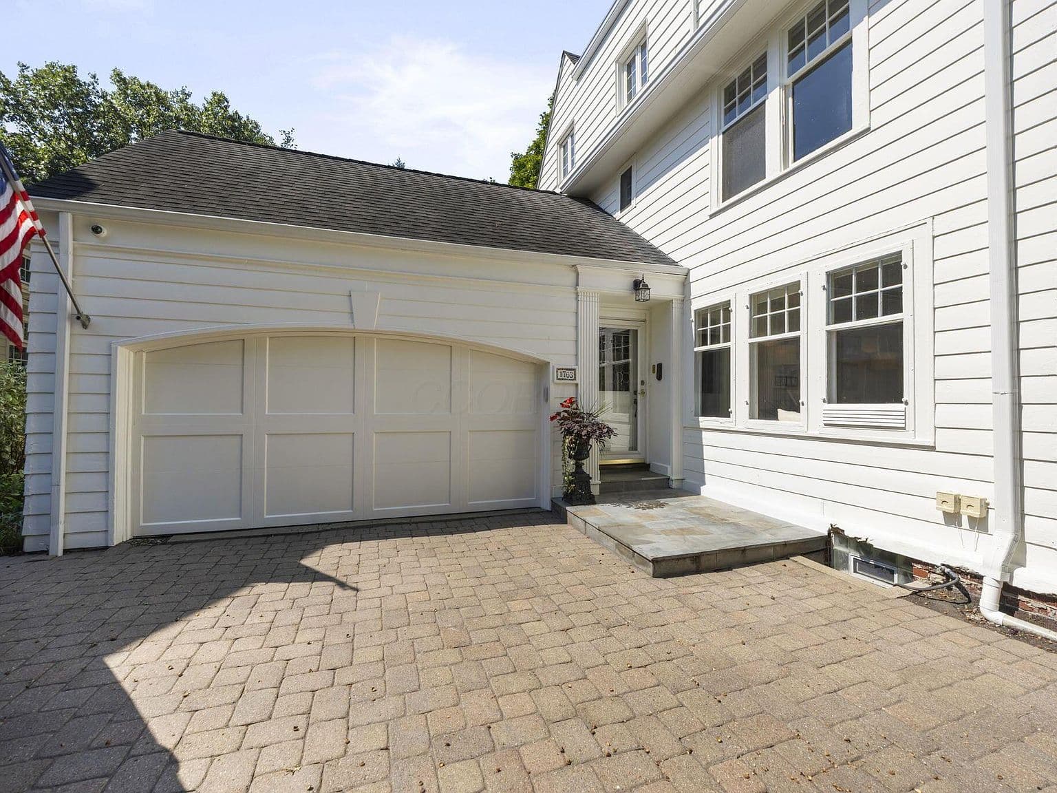 Paver driveway leads to oversized two-car garage entry.