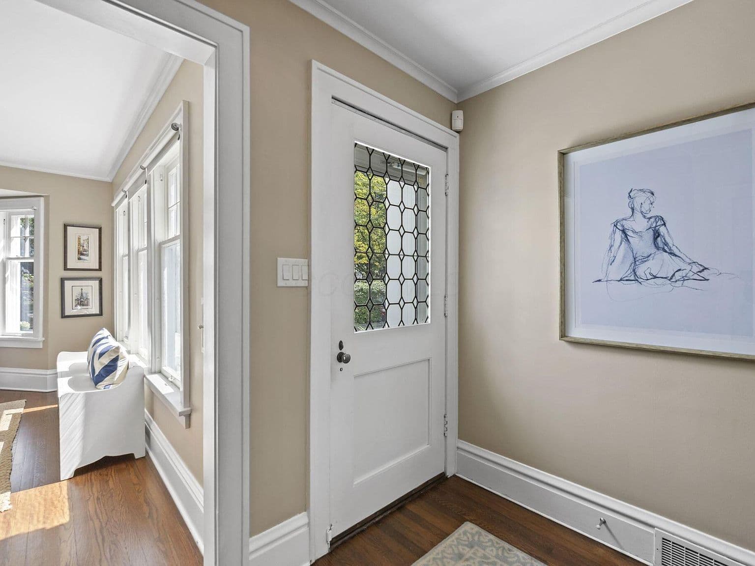 Sunlit foyer showcases warm wood floors and classic trim.