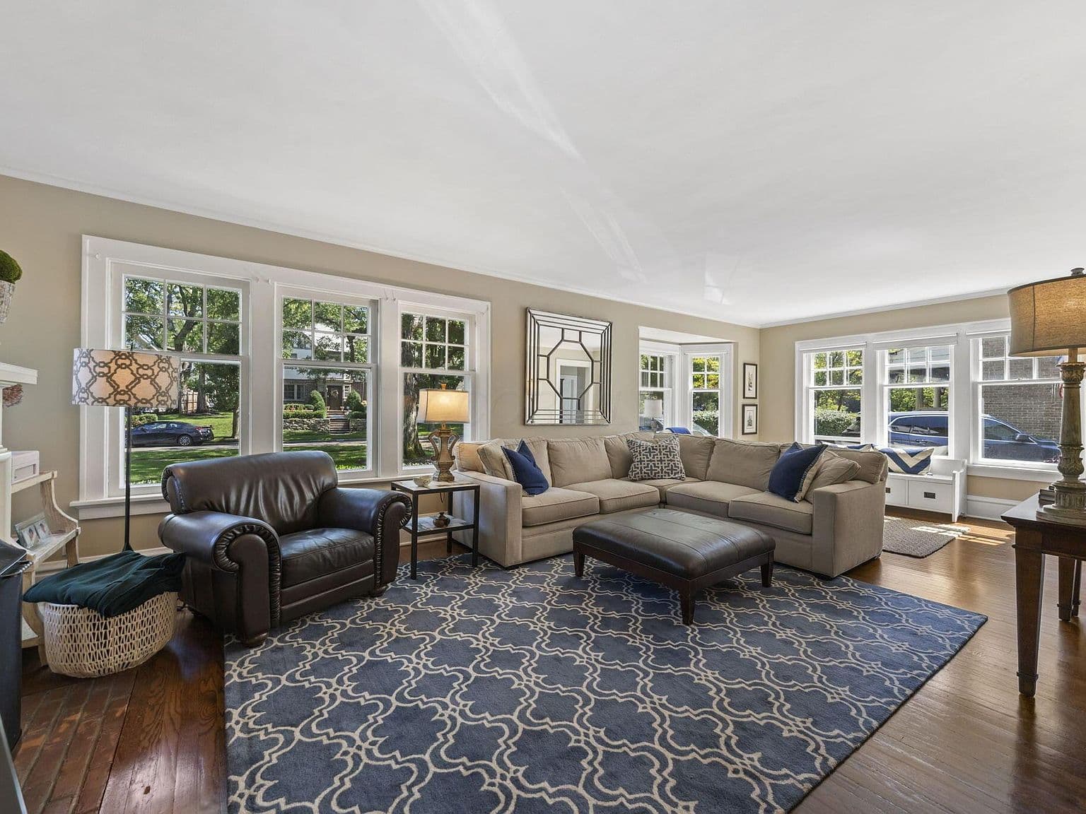 Sun-filled living room with picture windows and hardwoods.