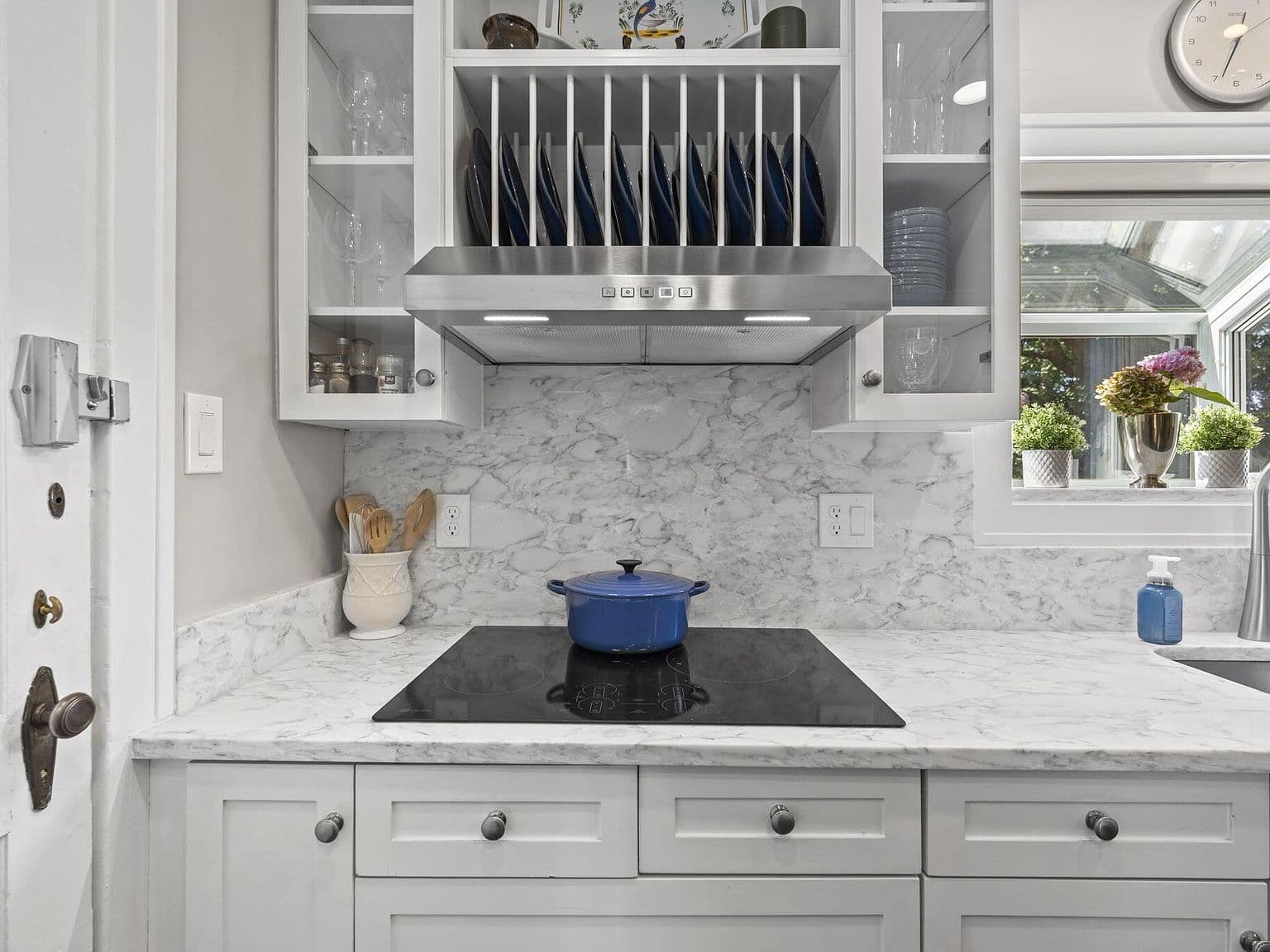 Marble backsplash and sleek cooktop in bright kitchen.