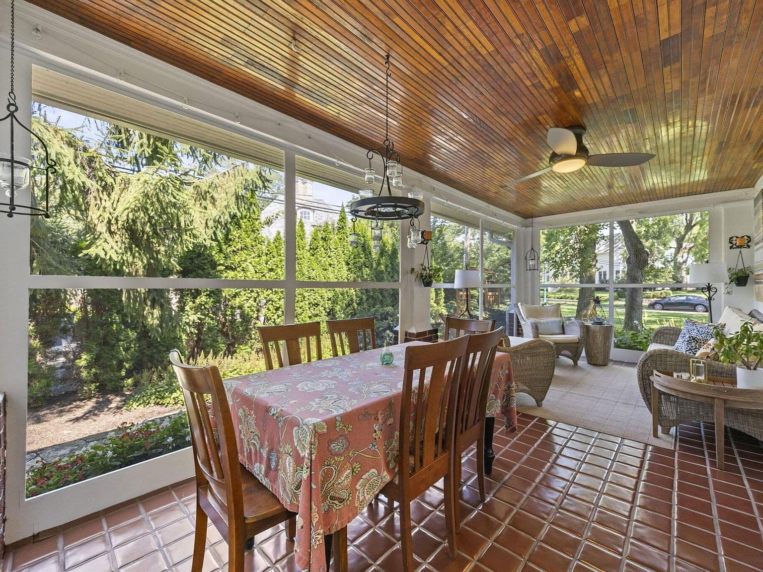 Screened porch dining with wood ceiling and garden views.