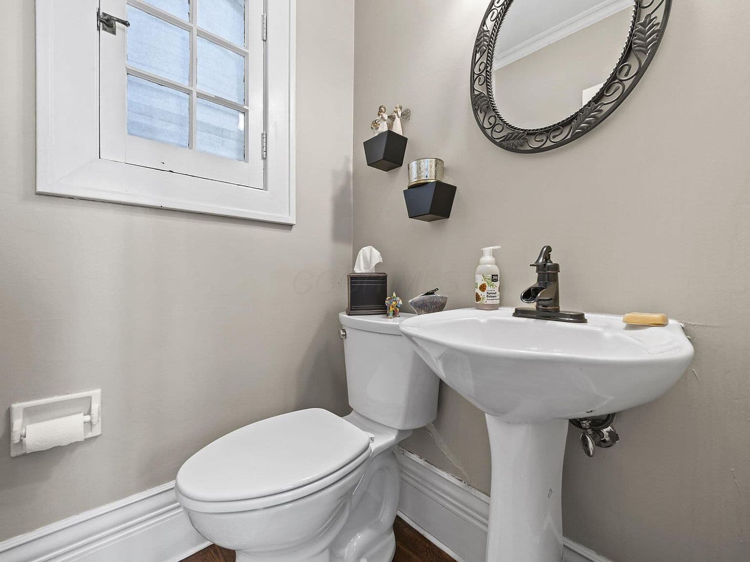 Stylish half bath with pedestal sink and modern mirror.