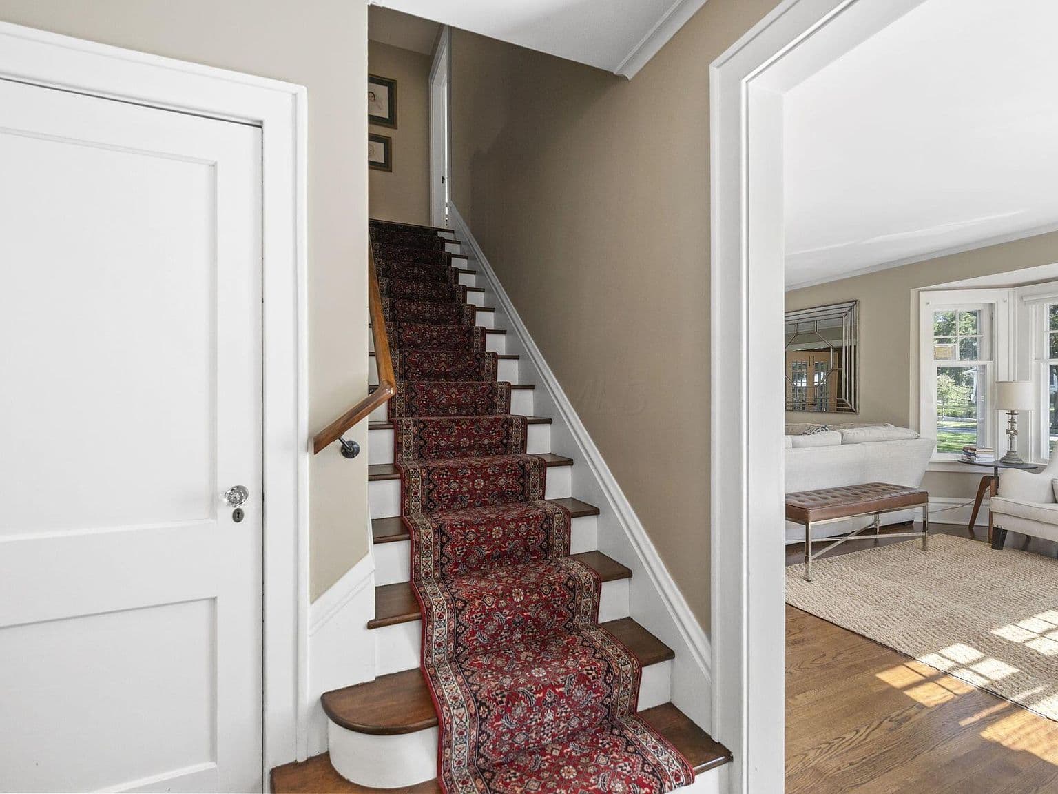 Grand staircase with runner and warm wood floors.