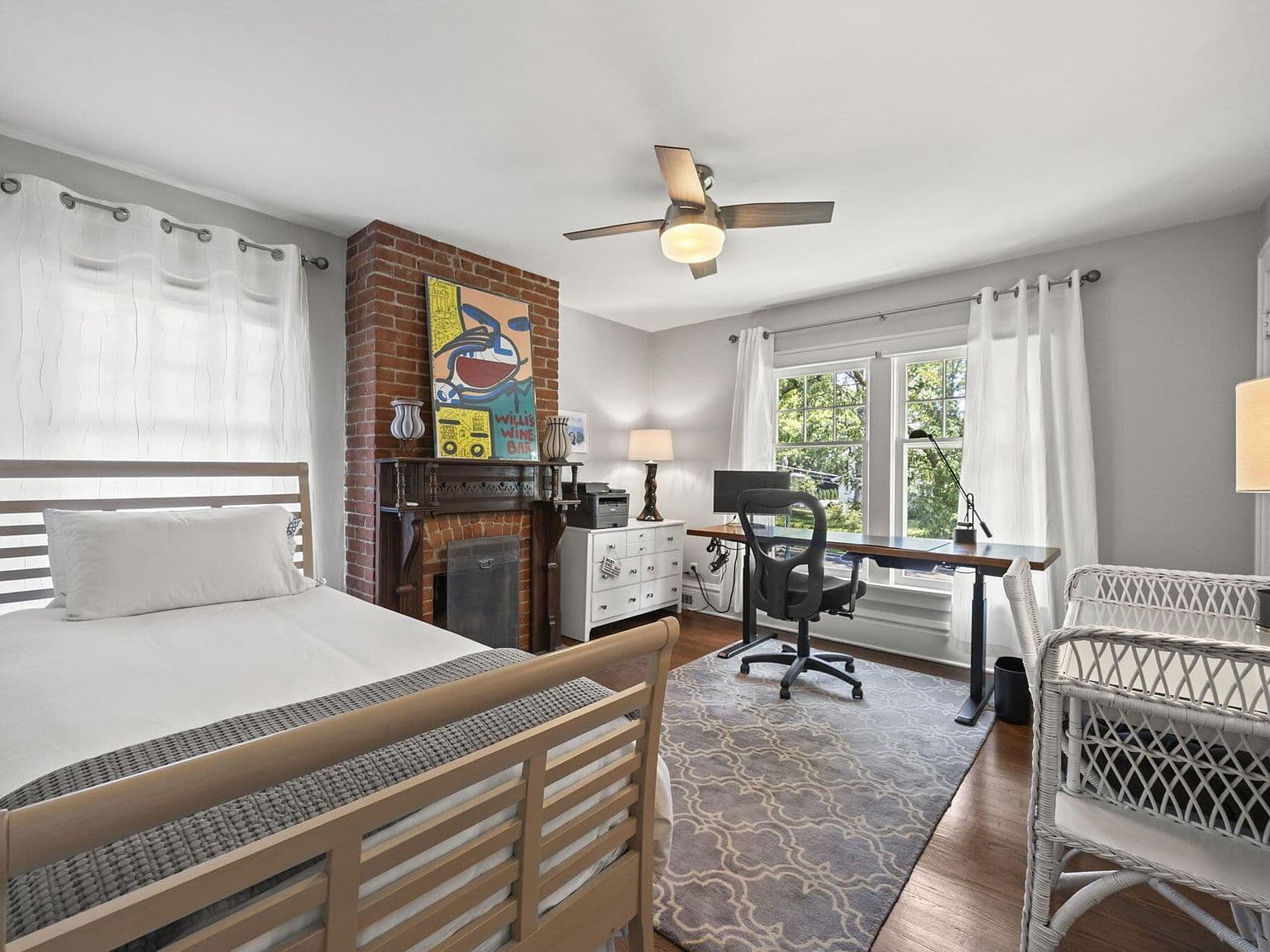 Versatile bedroom-office featuring charming decorative fireplace.