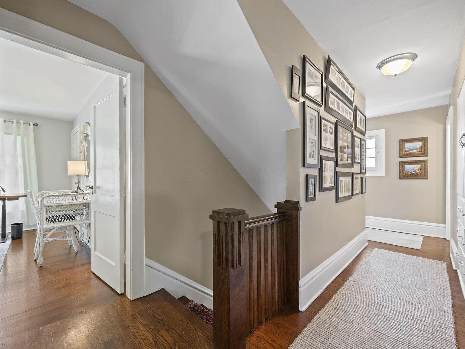 Upstairs hall with gallery wall and rich hardwoods.