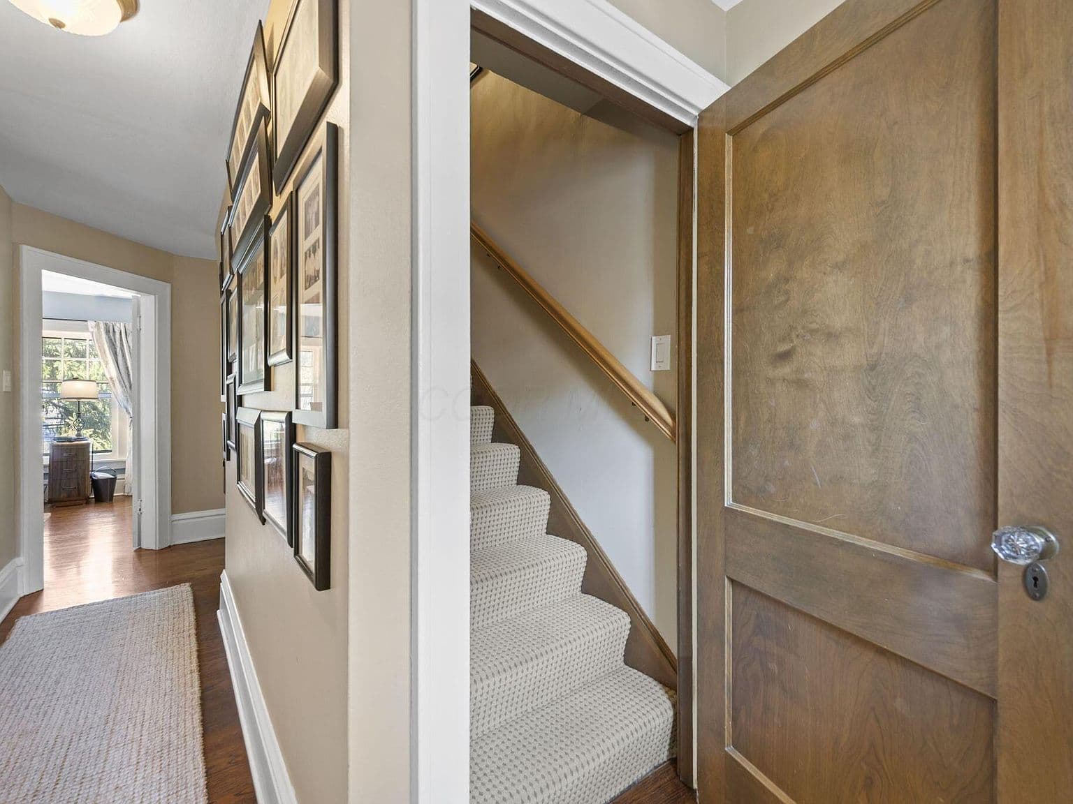 Hallway with staircase and gallery wall leading to bedrooms.