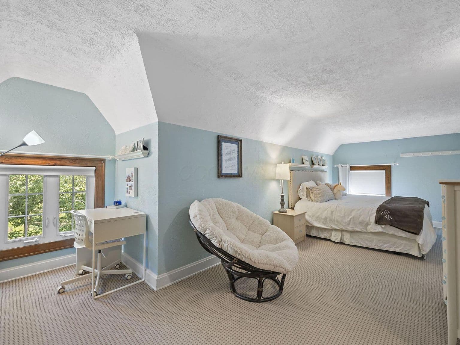 Charming upstairs bedroom with desk and lounge chair.