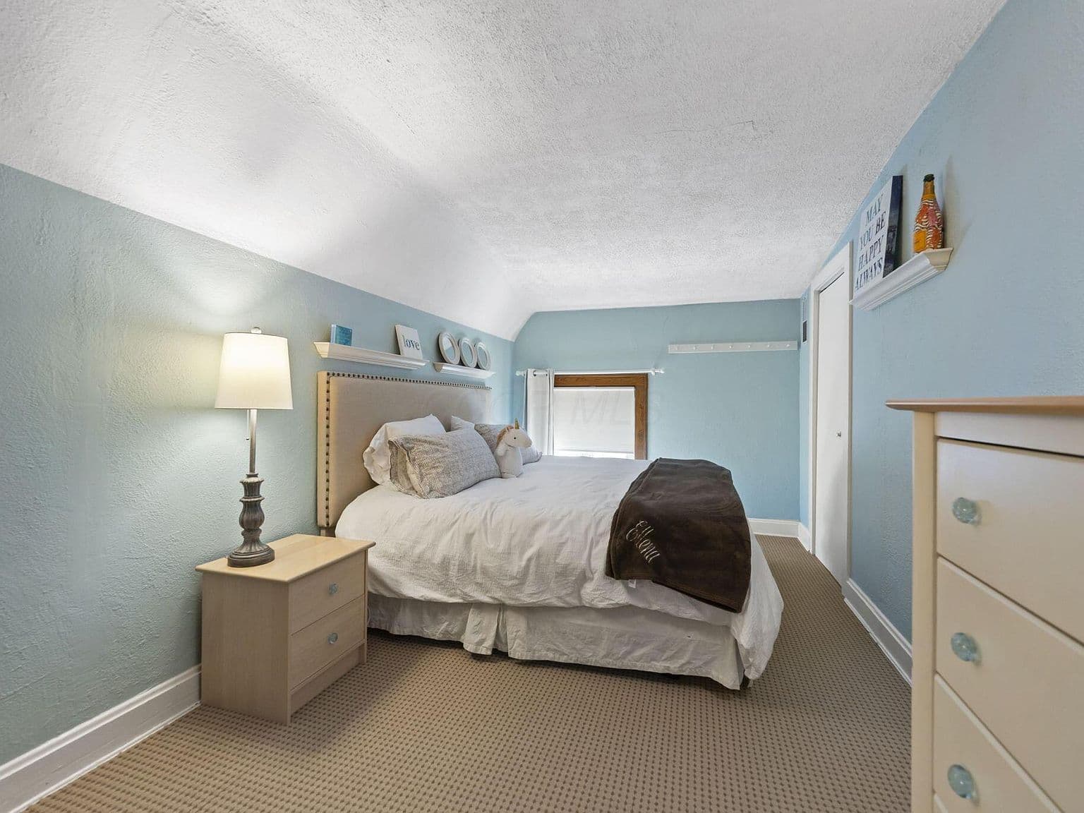 Serene attic bedroom with soft blue walls and storage.