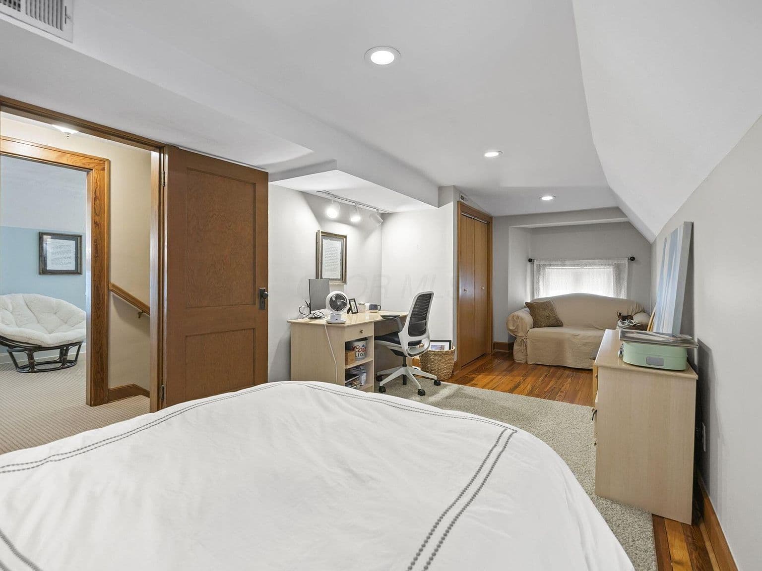 Loft-style bedroom with workspace and cozy seating corner.