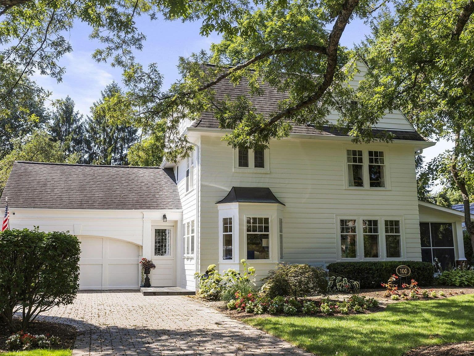Classic exterior with attached two-car garage and mature trees.