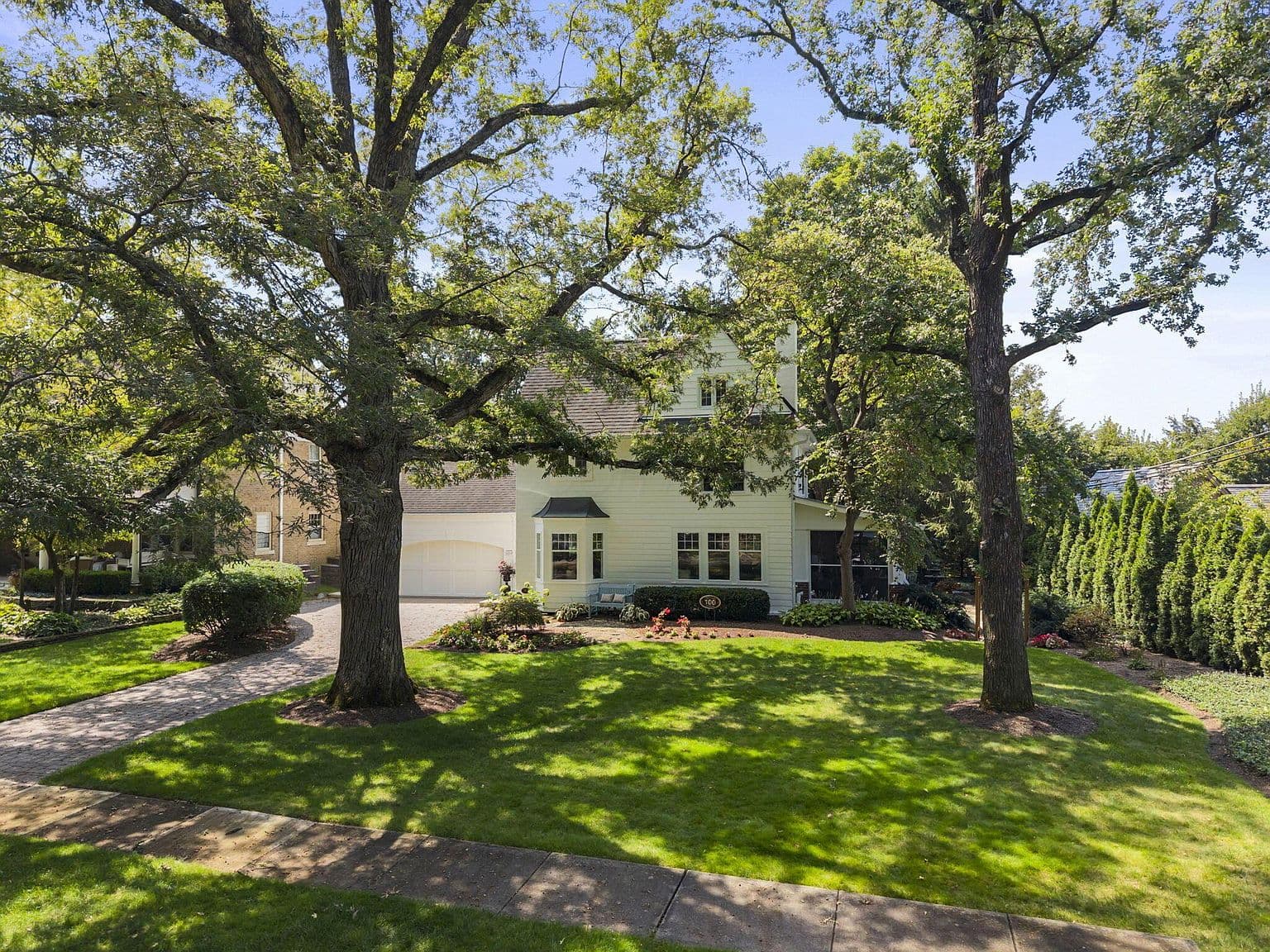 Stately front lawn with towering shade trees and curb appeal.