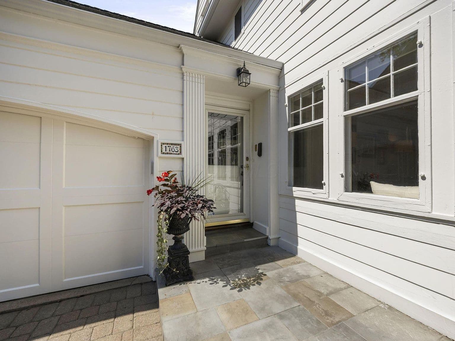 Inviting covered entry with stone landing and bright windows.