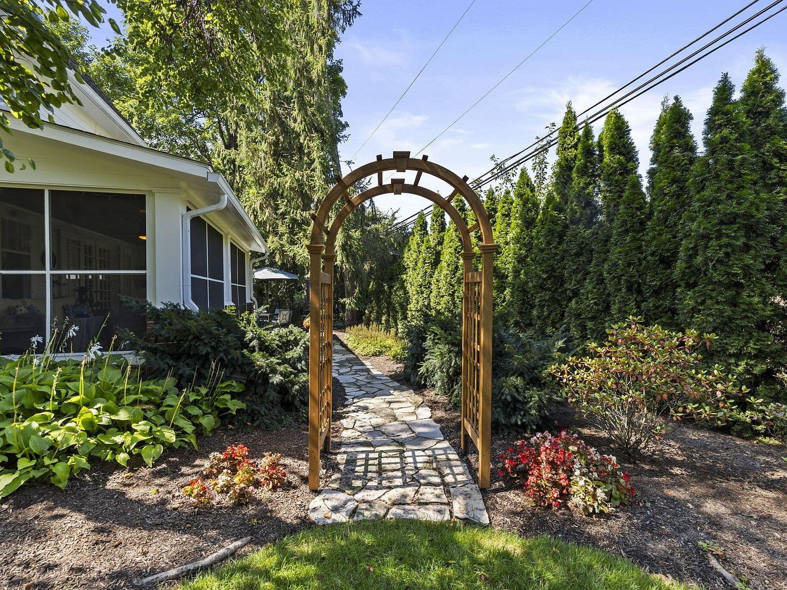 Garden arbor entry leading to serene screened porch retreat.