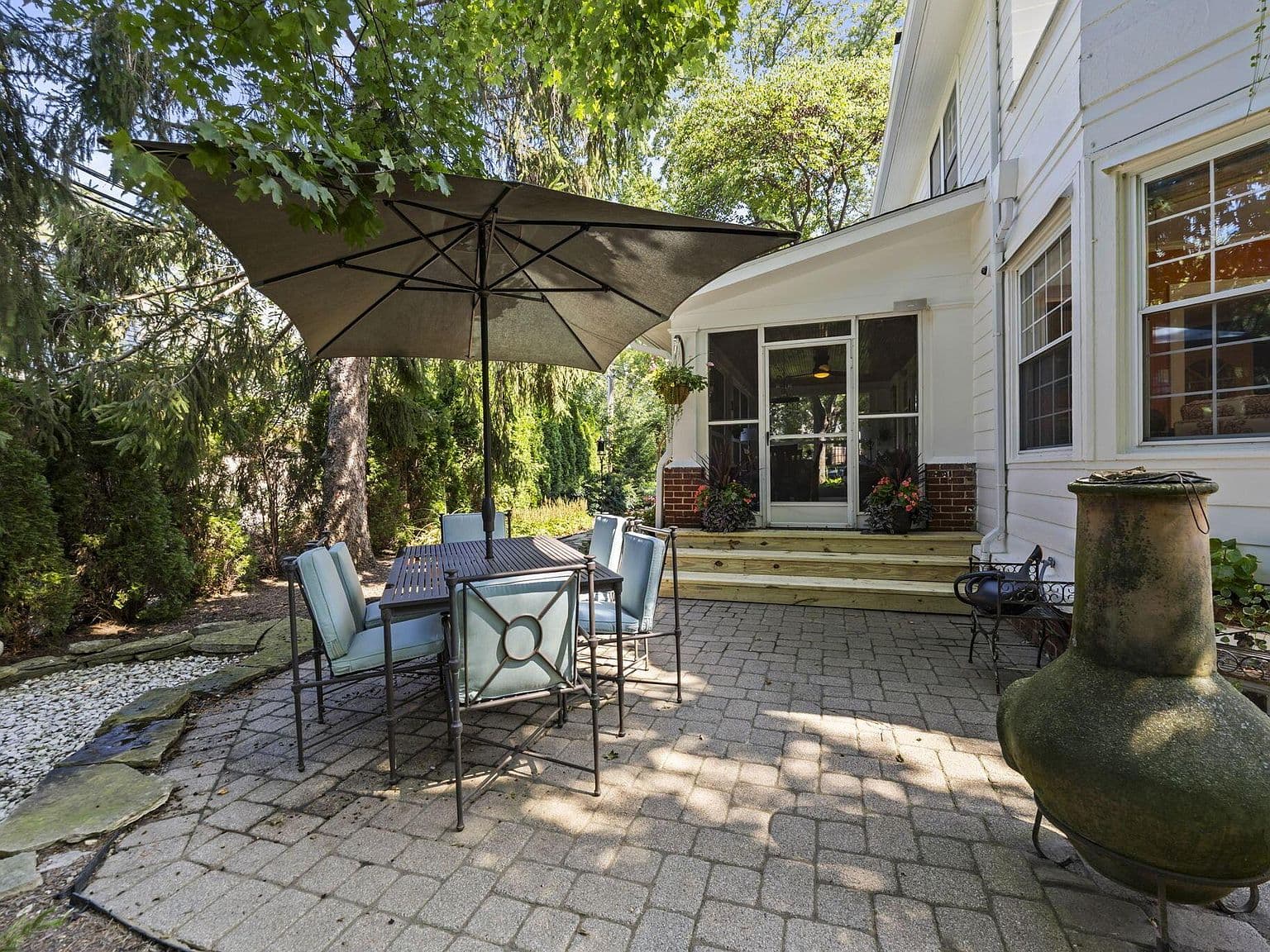 Shaded paver patio steps from the screened porch.
