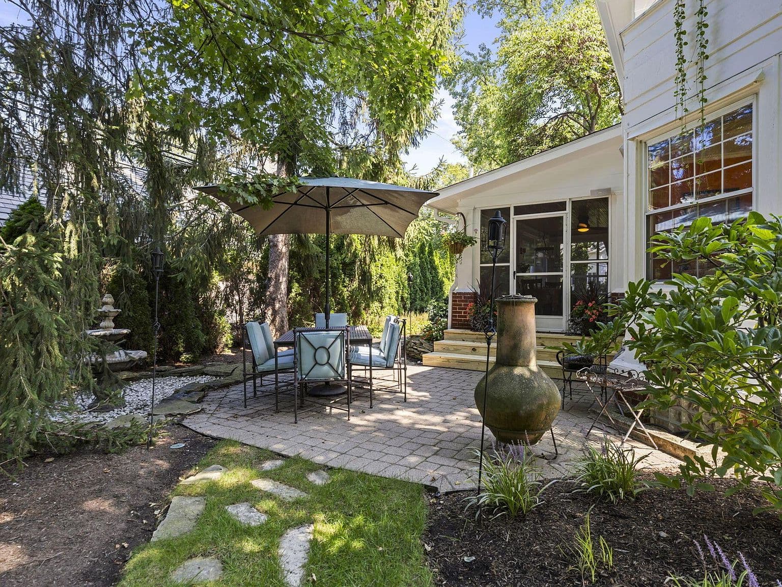 Charming outdoor dining nook surrounded by mature evergreens.