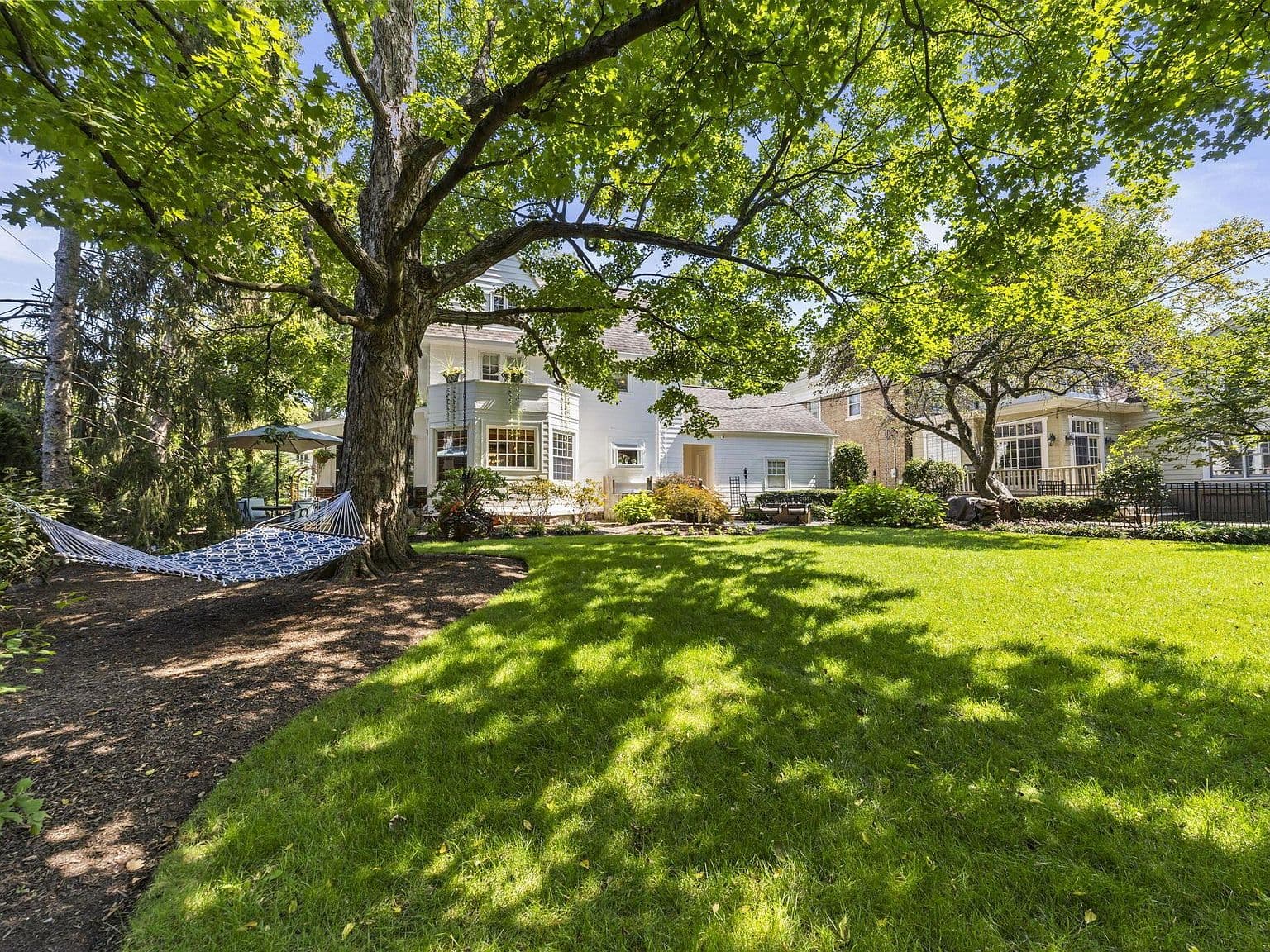 Expansive, tree-lined yard with a relaxing hammock spot.