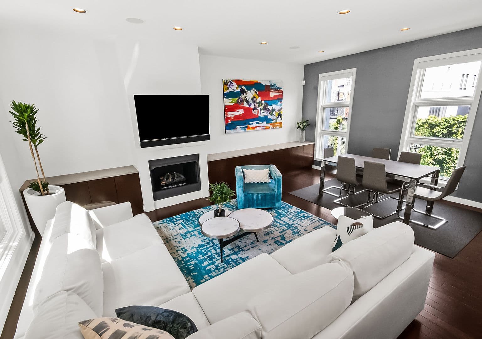 Sunlit open-concept living and dining with sleek fireplace.