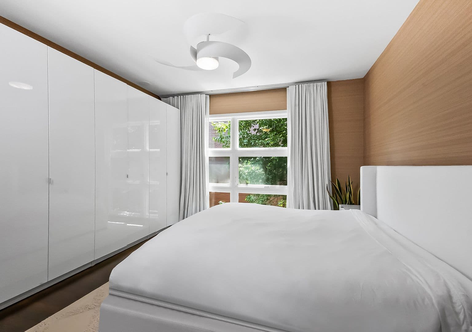 Serene primary suite with treetop views and built-in storage.